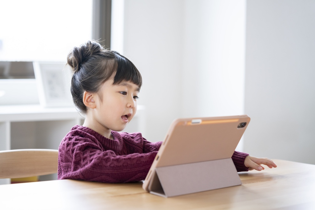 iPadでオンライン英会話をしている小学生